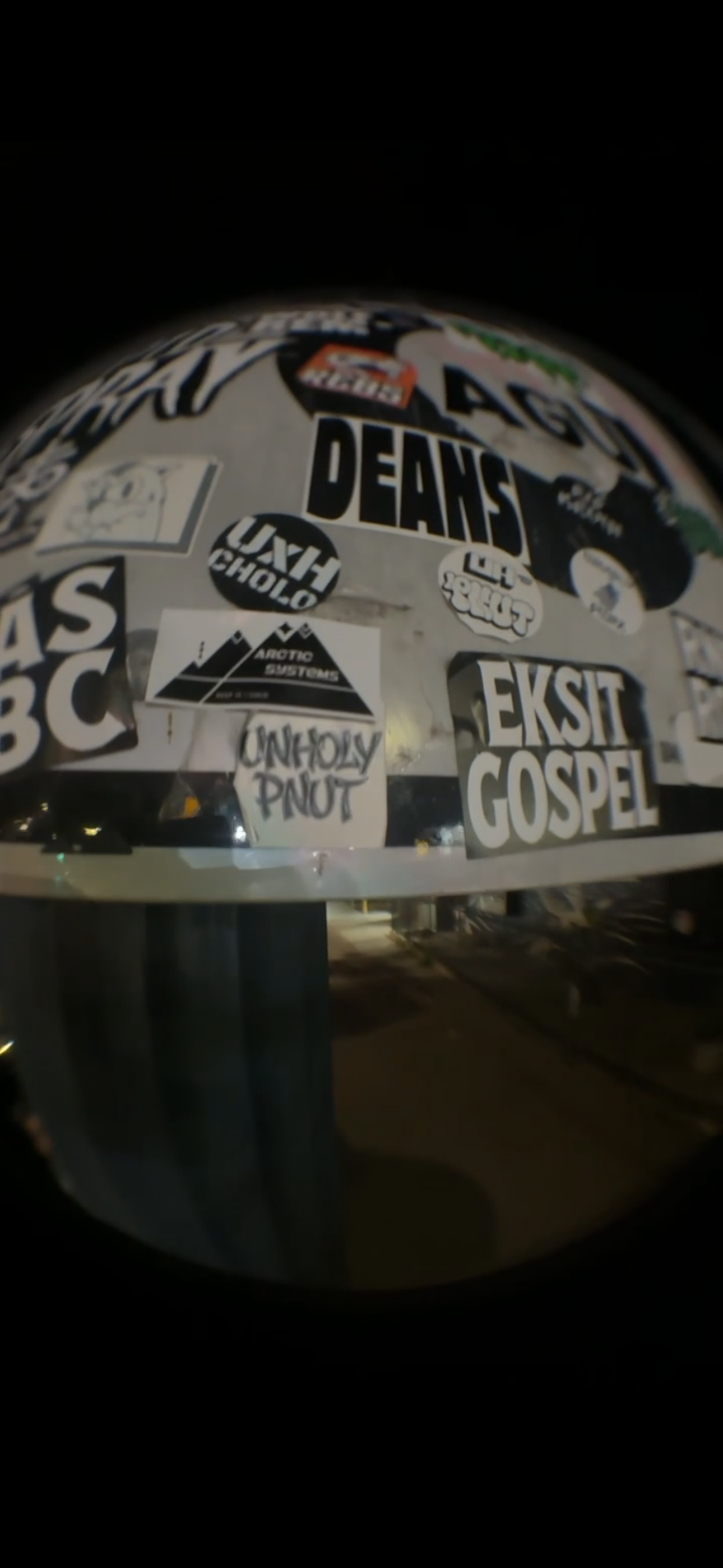 A fisheye night photograph of a sticker-covered pole with an Arctic Systems mountain-logo sticker